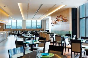a dining room with tables and chairs and windows at Aloft Dalian in Dalian