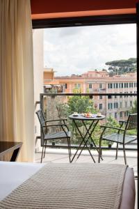 um quarto com uma varanda com uma mesa e cadeiras em Starhotels Michelangelo Rome em Roma