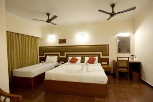 2 Betten in einem Hotelzimmer mit 2 Ventilatoren in der Unterkunft Breeze Residency in Tiruchchirāppalli + 37 Fotos
