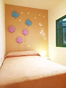 1 dormitorio con 1 cama con flores en la pared en Bonita casa cerca de la playa - Chalet Eras Costeras, en Las Eras