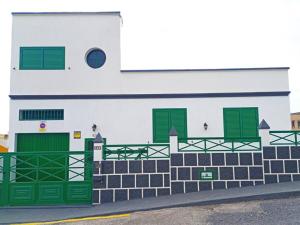 un bâtiment avec des portes et des fenêtres vertes dans une rue dans l'établissement Bonita casa cerca de la playa - Chalet Eras Costeras, à Las Eras