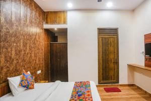 1 dormitorio con 1 cama y pared de madera en FabHotel Moon Gaze Inn, en Kānpur