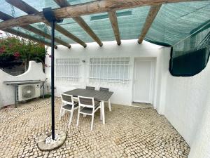 un patio avec une table et des chaises sous un toit dans l'établissement Quarteira Stylish 2 by Homing, à Quarteira