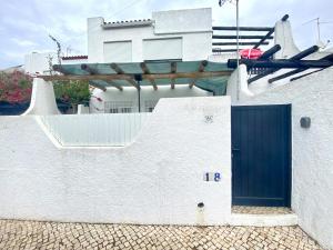 una casa blanca con una puerta azul y una valla en Quarteira Stylish 2 by Homing, en Quarteira