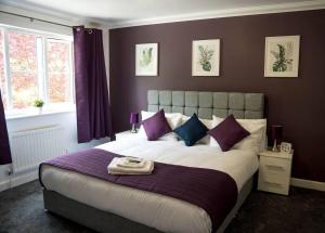 Remarkable 5-Bed House in Horley في هورلي: غرفة نوم بسرير كبير وبجدران ارجوانية