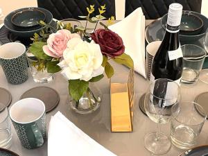 Remarkable 5-Bed House in Horley في هورلي: طاولة مع إناء من الزهور وزجاجة من النبيذ