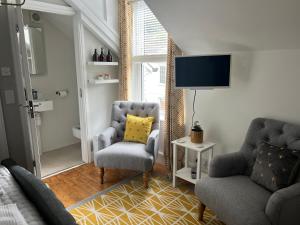uma sala de estar com duas cadeiras e uma televisão em The Captain's House em Looe