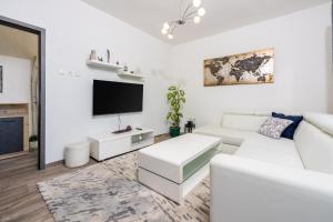 ein Wohnzimmer mit weißen Möbeln und einem Flachbild-TV in der Unterkunft ROZA in Dramalj