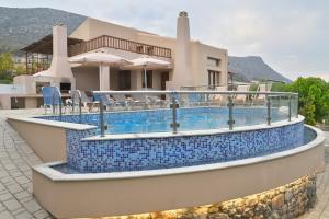 a swimming pool with blue tile around a house at Ida villa in Hersonissos