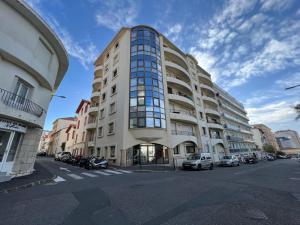 un edificio alto con coches estacionados frente a él en APPARTEMENT MODERNE ET SPACIEUX AU COEUR DE BIARRITZ 6 pers en Biarritz