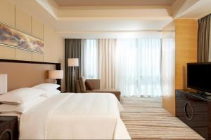 Gu'anにあるFour Points by Sheraton Langfang, Gu'anのベッドとテレビが備わるホテルルームです。