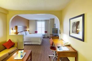 a hotel room with a bed and a desk and a couch at Four Points by Sheraton Charlotte/Pineville in Charlotte
