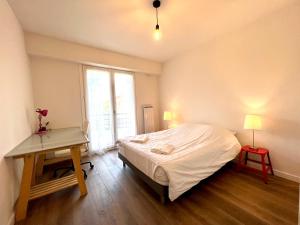 1 dormitorio con cama, escritorio y ventana en APPARTEMENT MODERNE ET SPACIEUX AU COEUR DE BIARRITZ 6 pers, en Biarritz