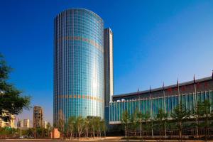 a tall glass building with a blue at Sheraton Jinzhou Hotel in Jinzhou