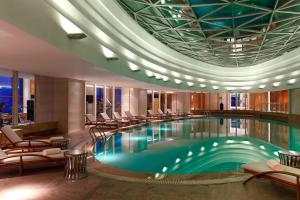 a swimming pool in a hotel lobby with chairs at Sheraton Jinzhou Hotel in Jinzhou
