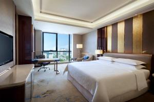 a bedroom with a bed and a desk and a television at Sheraton Grand Zhengzhou Hotel in Zhengzhou