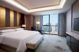 a bedroom with a large bed and a large window at Sheraton Grand Zhengzhou Hotel in Zhengzhou