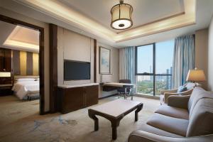um grande quarto de hotel com uma cama e uma televisão em Sheraton Grand Zhengzhou Hotel em Zhengzhou