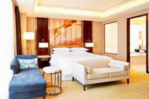 a bedroom with a bed and a couch and a chair at Sheraton Grand Zhengzhou Hotel in Zhengzhou