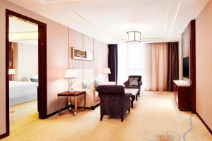a hotel room with a chair and a bedroom at Sheraton Grand Zhengzhou Hotel in Zhengzhou