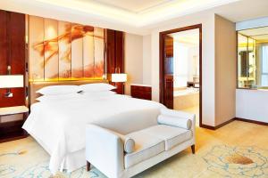 a bedroom with a large white bed and a couch at Sheraton Grand Zhengzhou Hotel in Zhengzhou