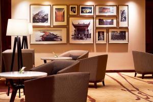 a waiting room with tables and chairs and pictures on the wall at Sheraton Grand Zhengzhou Hotel in Zhengzhou