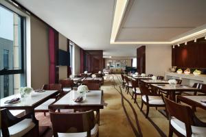 um restaurante com mesas e cadeiras de madeira e uma grande janela em Sheraton Grand Zhengzhou Hotel em Zhengzhou
