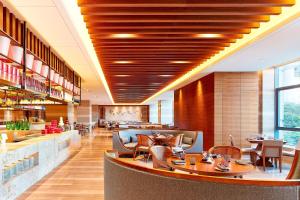 a restaurant with wooden ceilings and tables and chairs at Sheraton Grand Zhengzhou Hotel in Zhengzhou