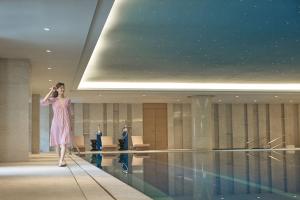a woman in a pink dress standing next to a swimming pool at Sheraton Grand Zhengzhou Hotel in Zhengzhou