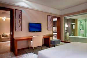 a hotel room with a bed and a desk and a television at Four Points by Sheraton Taicang in Taicang