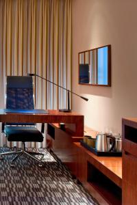 a room with a desk and a chair and a mirror at Four Points by Sheraton Taicang in Taicang