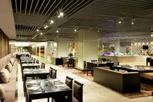 a restaurant with tables and chairs and a bar at Four Points by Sheraton Qingdao, West Coast in Huangdao