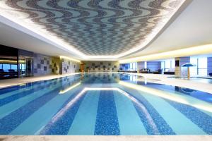 a large swimming pool in a building with a ceiling at Four Points by Sheraton Qingdao, West Coast in Huangdao
