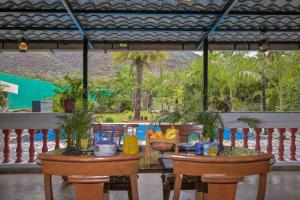a table and chairs with a view of a pool at Lifeline Villas - The Secret Place Lonavala With Huge Pool And Lawn Area in Lonavala