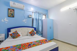 a bedroom with a bed with a blue wall at FabExpress JMD Inn in Lucknow