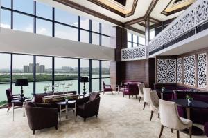 a lobby with tables and chairs and windows at Sheraton Shunde Hotel in Shunde