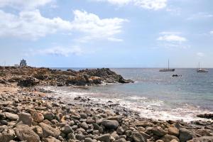 une plage rocheuse avec des bateaux dans l'eau dans l'établissement Cozy Fraile, à Las Galletas