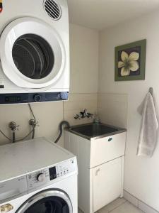 a kitchen with a washing machine and a microwave at A touch of lux in the Redlands! in Capalaba