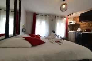 um quarto com uma grande cama branca com almofadas vermelhas em Appartement jacuzzi privatif : Urban Love em Verneuil d’Avre et d’Iton