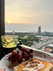 a plate of food with grapes and a drink on a table at Baan Kiang Fah by Thita Sea View in Hua Hin