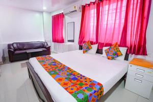 um quarto com uma cama grande e cortinas vermelhas em FabExpress Lloyds Inn I em Chennai