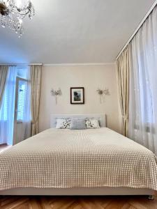 a bed in a bedroom with curtains and a chandelier at Апартаменты в самом центре столицы. in Kyiv