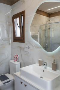 a bathroom with a sink and a toilet and a mirror at ALBA SUITE APARTMENT in Kalabaka +19 photos