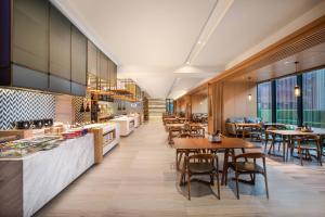 un restaurante con mesas, sillas y ventanas en Fairfield by Marriott Taiyuan South, en Taiyuán