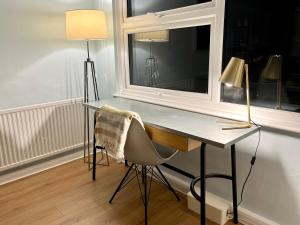 a desk with a lamp and a chair next to a window at Superhost's Amazing Spacious Flat with Great Links in London