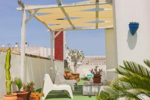 a patio with white chairs and a wooden pergola at Los Cantaros in El Puerto de Santa María