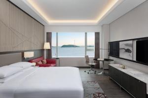 Courtyard by Marriott Xiamen Haicang في شيامن: غرفة فندقية بسرير كبير وتلفزيون بشاشة مسطحة
