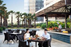 Ein Mann und eine Frau sitzen an Tischen in einem Restaurant in der Unterkunft Courtyard by Marriott Xiamen Haicang in Xiamen