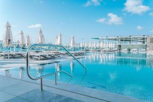 - une piscine avec des chaises longues et des parasols dans l'établissement Valletta view Apartments by ST Hotels, à Il- Gżira