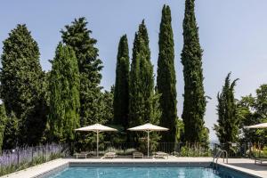 una piscina con sombrillas, sillas y árboles en Relais Roncolo 1888, en Quattro Castella